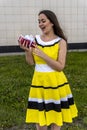 Portrait of a young beautiful girl in a smart dress with a gift near the shopping center, happy and smiling woman Royalty Free Stock Photo