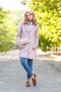 Portrait of a young beautiful girl in a pink coat. In the park. Royalty Free Stock Photo