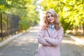 Portrait of a young beautiful girl in a pink coat. In the park. Royalty Free Stock Photo