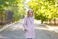 Portrait of a young beautiful girl in a pink coat. In the park. Royalty Free Stock Photo