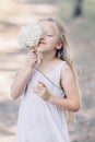 Portrait of a young beautiful girl who hides part of her face behind a hydrangea and smiles Royalty Free Stock Photo
