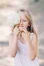 Portrait of a young beautiful girl who hides part of her face behind a hydrangea and smiles Royalty Free Stock Photo