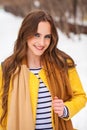 Beautiful girl in yellow coat posing on a background of a winter park Royalty Free Stock Photo