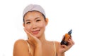 Young beautiful and happy Asian Chinese woman applying skincare wrinkle prevention serum treatment or aging beauty product on her