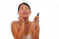 Young beautiful and happy Asian Korean woman applying skincare wrinkle prevention serum treatment or aging beauty product on her
