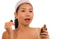 Young beautiful and happy Asian Korean woman applying skincare wrinkle prevention serum treatment or aging beauty product on her