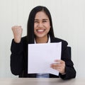 Portrait of young beautiful and happy Asian woman wearing smart casual laughing with friendly and cheerful face holding paper