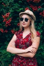 Portrait of young beautiful blonde long haired smiling teenage girl in sunglasses wearing red dress over green Royalty Free Stock Photo
