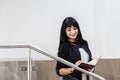 Portrait of Young Beautiful happy brunette woman dressed in a black business suit working with a notebook, standing in office, Royalty Free Stock Photo