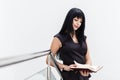 Portrait of Young Beautiful happy brunette woman dressed in a black business suit working with a notebook, standing in office, Royalty Free Stock Photo