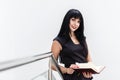 Portrait of Young Beautiful happy brunette woman dressed in a black business suit working with a notebook, standing in a office, Royalty Free Stock Photo