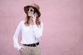 Portrait of a beautiful happy business woman in sunglasses,a hat outdoors talking on the phone on a pink background Royalty Free Stock Photo