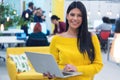 Portrait of young beautiful happy casual businesswoman standing with laptop at her workplace inside modern co working space Royalty Free Stock Photo