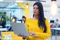 Portrait of young beautiful happy casual businesswoman standing with laptop at her workplace inside modern co working space Royalty Free Stock Photo