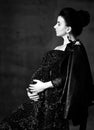 Portrait of young beautiful happy pregnant woman in black lace dress and leather jacket standing and embracing belly, side view Royalty Free Stock Photo