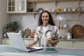 Portrait of young beautiful hispanic woman at home, female freelancer working remotely using laptop, looking at camera Royalty Free Stock Photo