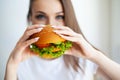 Portrait of young beautiful hungry woman eating burger.