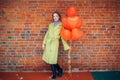 Portrait of young and beautiful lady in coat with red air balloons