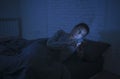 Portrait of young beautiful latin woman using mobile phone late night sleepless lying in bed in the dark in smartphone and interne Royalty Free Stock Photo