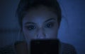 Portrait of young beautiful latin woman using mobile phone late night sleepless lying in bed in the dark in smartphone and interne Royalty Free Stock Photo