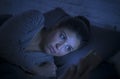 Portrait of young beautiful latin woman using mobile phone late night sleepless lying in bed in the dark in smartphone and interne Royalty Free Stock Photo