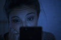 Portrait of young beautiful latin woman using mobile phone late night sleepless lying in bed in the dark in smartphone and interne Royalty Free Stock Photo