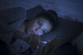 Portrait of young beautiful latin woman using mobile phone late night sleepless lying in bed in the dark in smartphone and interne Royalty Free Stock Photo