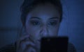 Portrait of young beautiful latin woman using mobile phone late night sleepless lying in bed in the dark in smartphone and interne Royalty Free Stock Photo