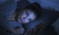 Portrait of young beautiful latin woman using mobile phone late night sleepless lying in bed in the dark in smartphone and interne Royalty Free Stock Photo