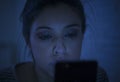 Portrait of young beautiful latin woman using mobile phone late night sleepless lying in bed in the dark in smartphone and interne Royalty Free Stock Photo