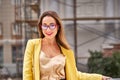 Portrait of a young beautiful laughing woman with long hair wearing glasses and a yellow jacket Royalty Free Stock Photo