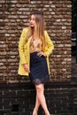 Portrait of a young beautiful laughing woman with long hair  and a yellow jacket against the background of a brick wall Royalty Free Stock Photo