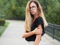 Portrait of young beautiful long hair woman wearing black blouse, holding mobile phone at summer green park path background. Royalty Free Stock Photo