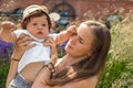 Portrait of a young beautiful mother with a moody and naughty little child baby boy in her arms on a summer day outdoors. Royalty Free Stock Photo