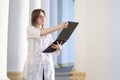 Portrait of a young nurse, a medical university student stands with a phonendoscope and reads a paper, happy female doctor in Royalty Free Stock Photo