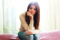 Portrait of a young beautiful pensive woman sitting on sofa Royalty Free Stock Photo