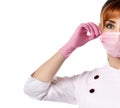 Portrait of young beautiful red-haired woman doctor or nurse in white special uniform and gloves putting mask on face
