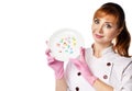 Portrait of young beautiful red-haired woman doctor or nurse in white special uniform and gloves showing plate with colorful pills Royalty Free Stock Photo