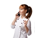 Portrait of young beautiful red-haired woman doctor or nurse in white special uniform standing and talking on phone Royalty Free Stock Photo