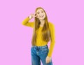 Portrait of a young beautiful red-haired woman standing and looking at the camera and showing holding fingers near Royalty Free Stock Photo