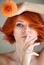 Portrait of young beautiful redhaired woman with orange flower. Finger on lips silent gesture Royalty Free Stock Photo