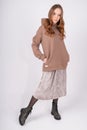 Portrait of young beautiful redhead woman in cozy clothes. Sexy female fashion model poses in taupe hoodie and skirt on white Royalty Free Stock Photo