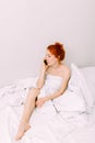 Portrait of a young beautiful redhead woman talking on the phone in bed Royalty Free Stock Photo