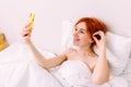 Portrait of a young beautiful redhead woman talking on the phone in bed Royalty Free Stock Photo