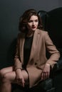 Portrait of young, beautiful sad woman with short brown hair with stylish make up in black dress and beige jacket Royalty Free Stock Photo