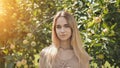 Portrait of a young beautiful seventeen-year-old blonde girl in the apple orchard. Royalty Free Stock Photo