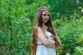 Portrait of a young beautiful Slavic girl with long hair and a Slavic ethnic dress on a background of green grass