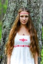 Portrait of a young beautiful Slavic girl with long hair and Slavic ethnic dress in a summer forest Royalty Free Stock Photo