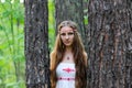 Portrait of a young beautiful Slavic girl with long hair and Slavic ethnic dress in a summer forest