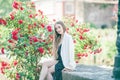 Portrait of a young beautiful slim long-haired woman in a romantic black and white dress near a red blooming rose in the center of Royalty Free Stock Photo